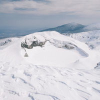 蔵王の御釜火口湖を望む雪に覆われた山頂景色の写真