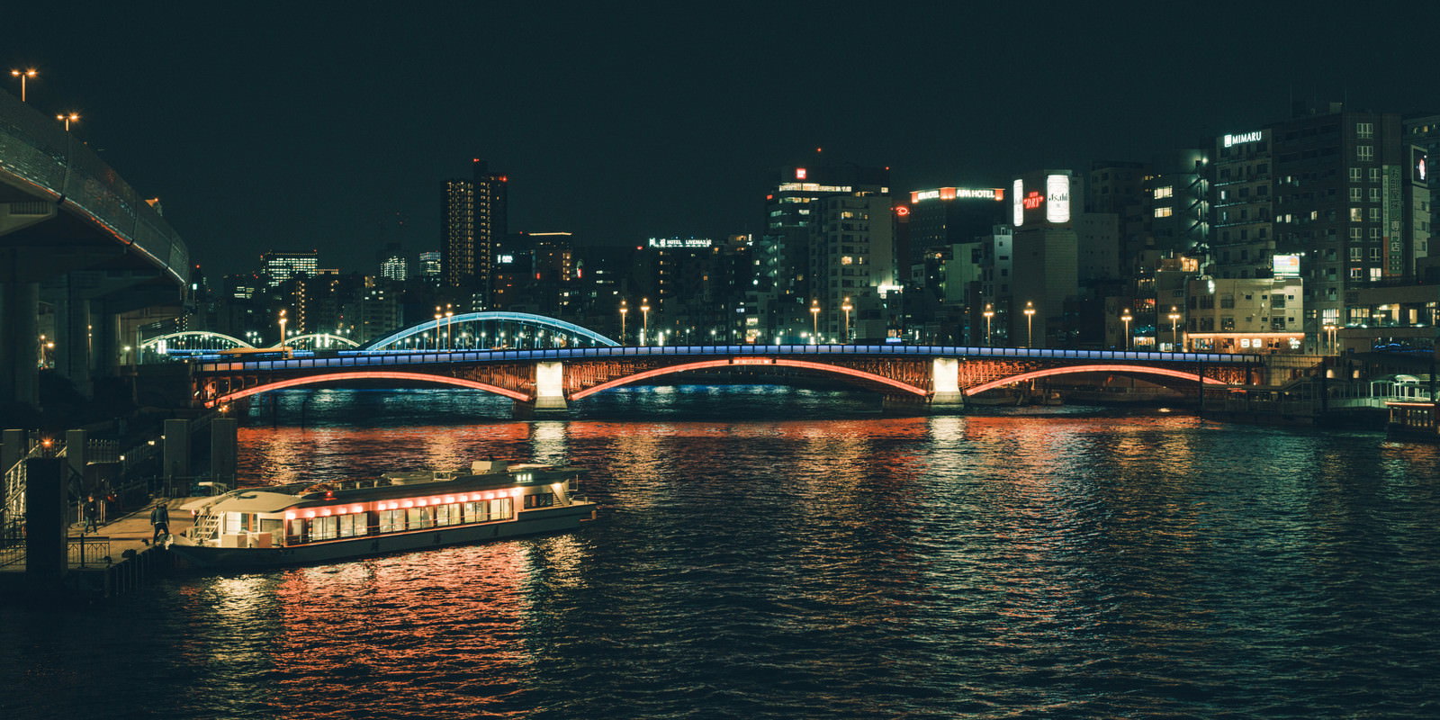 隅田川でライトアップされた橋と水上バスが映る夜景