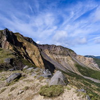雲が飛び交う磐梯山の険しい稜線と活火山の岩肌の写真