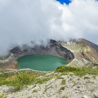 エメラルドグリーンに輝く蔵王山の御釜と山上の雲の写真