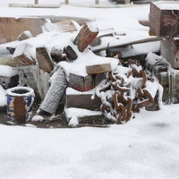 冬の積雪に埋もれた錆び付いた鎖と廃材、風雪にさらされた痕跡の写真
