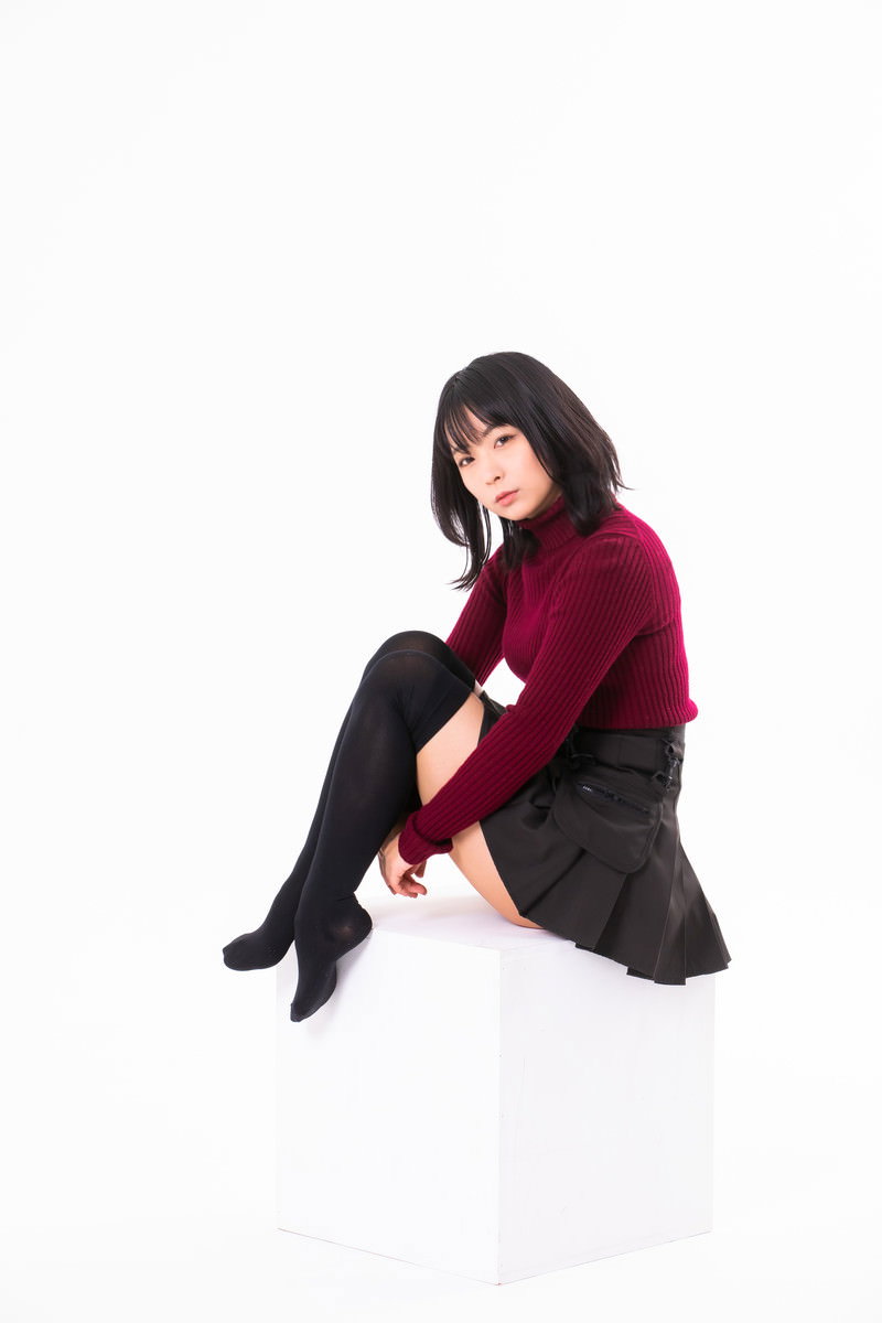 床に座って膝を抱える小山座りのポーズをとる赤い服の女性［モデル：にゃるる］