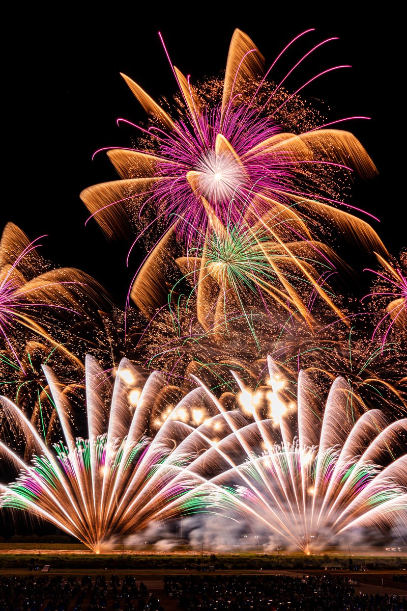 黒い夜空に色とりどりの打上げ花火が一斉に爆発している様子