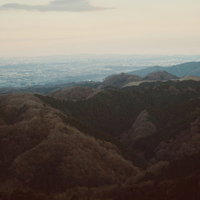 高所から眺める街並みと低山の遠景、平野と建物が広がる俯瞰風景の写真