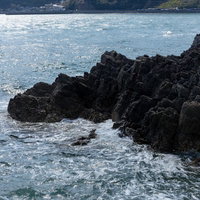 磐台寺の崖下に打ち寄せる波と黒い岩肌の海岸風景の写真
