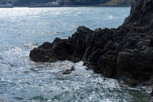 磐台寺の崖下に打ち寄せる波と黒い岩肌の海岸風景