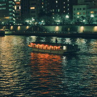 隅田川の夜景に浮かぶ屋形船と水上バスのライトアップ風景の写真