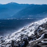 身が凍える寒さと強風で舞い上がる雪の白煙、蓼科山の岩場の写真