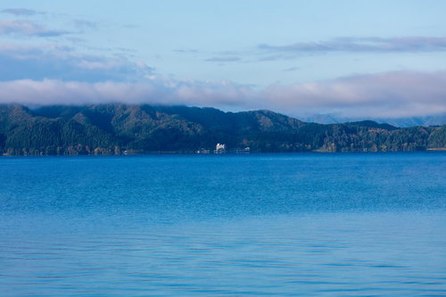 朝焼けの田沢湖に立つさざ波と秋田の山々に映える雲