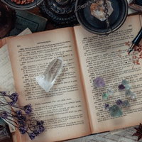 散らかった魔女の机に広げられた古書と魔法の道具の写真