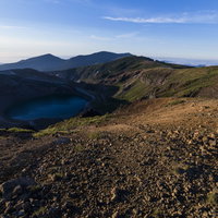 午前の陽光で日陰になった御釜・蔵王山の火山口湖の写真