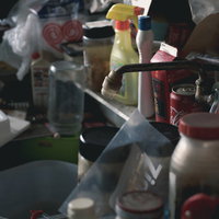 物で溢れ散らかった台所のシンク周りと調理器具の写真