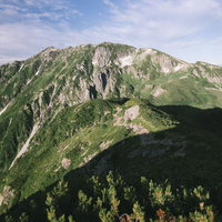 笠ヶ岳への稜線で見る絶壁と緑の山肌、北アルプスの雄大な山容の写真