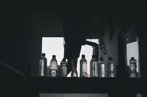 窓際に並ぶペットボトルの背くらべ、複数本のシルエット