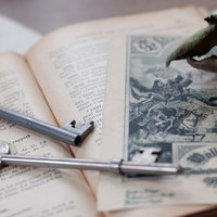 朽ちたバラと古い鍵が置かれた開かれた洋書の写真