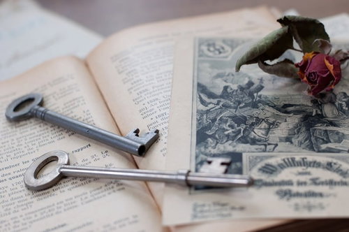 朽ちたバラと古い鍵が置かれた開かれた洋書