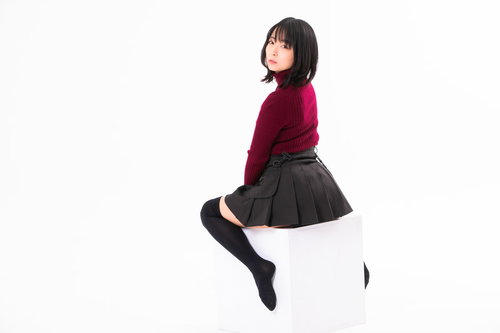 白い箱に跨って振り返る女性の写真