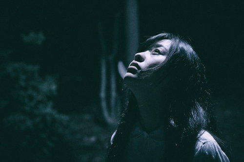 月の明かりが私を照らす暗闇の中で絶望する女性のホラー