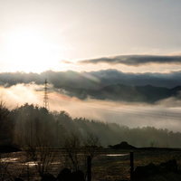 雲海に浮かぶ山間の鉄塔と送電線の絶景 朝焼けの田舎風景の写真