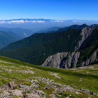 空に浮かぶ中央アルプスの山々と高山植物の雄大な風景の写真