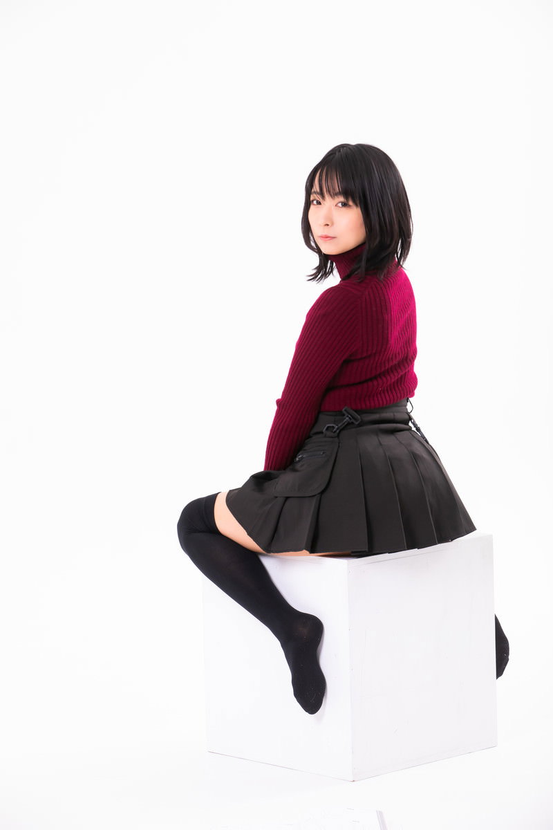 白い椅子に腰を掛けてポーズを取る、えんじ色ニット姿の女性［モデル：にゃるる］