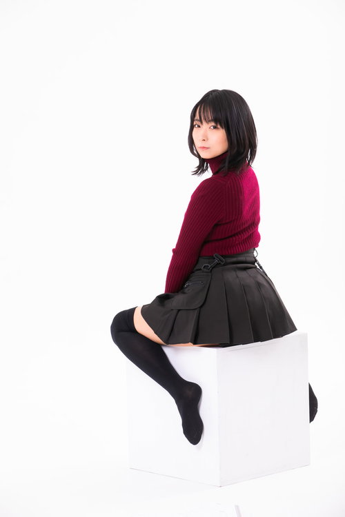 白い四角い椅子に腰を掛けて振り返る女性のポーズ