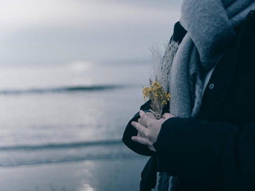 海辺でドライフラワーを持つグレーコートの学生