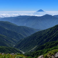 空に顔を出す富士山と連なる山脈の稜線と登山道の写真