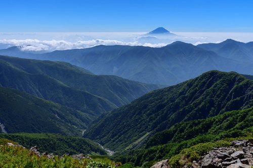 空に顔を出す富士山と連なる山脈の稜線と登山道