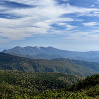吾妻山の深い森越しに見える安達太良山と日本百名山の景観の写真