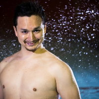 プールサイドで水しぶきを浴びて笑う男性の楽しい夏の時間の写真