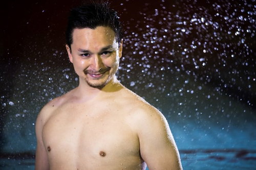 プールサイドで水しぶきを浴びて笑う男性の楽しい夏の時間