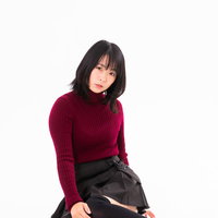 赤いセーターで横座りポーズをとる女性のポートレート撮影の写真