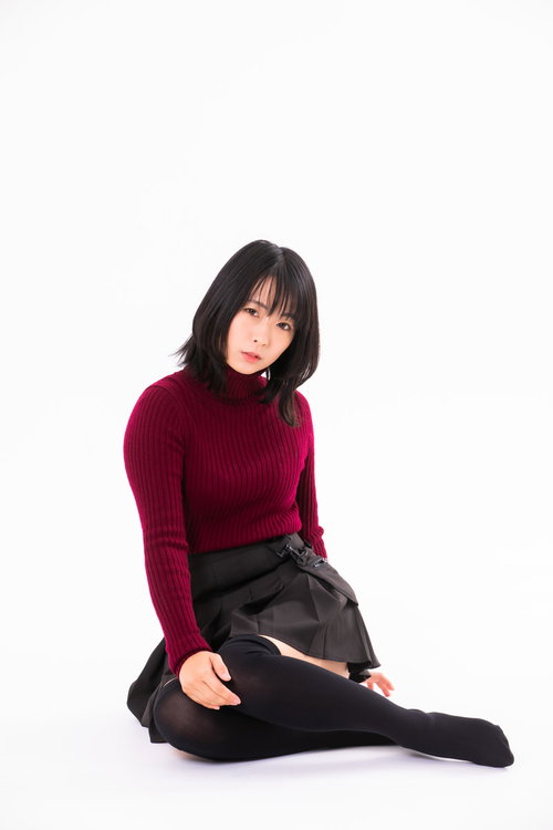 赤いセーターで横座りポーズをとる女性のポートレート撮影