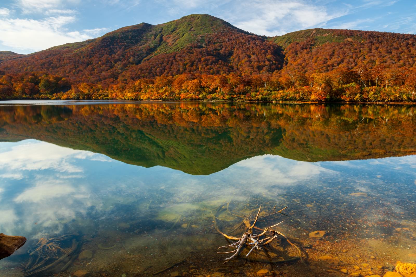 紅葉した山々が須川湖の静かな湖面に映り込む秋の風景