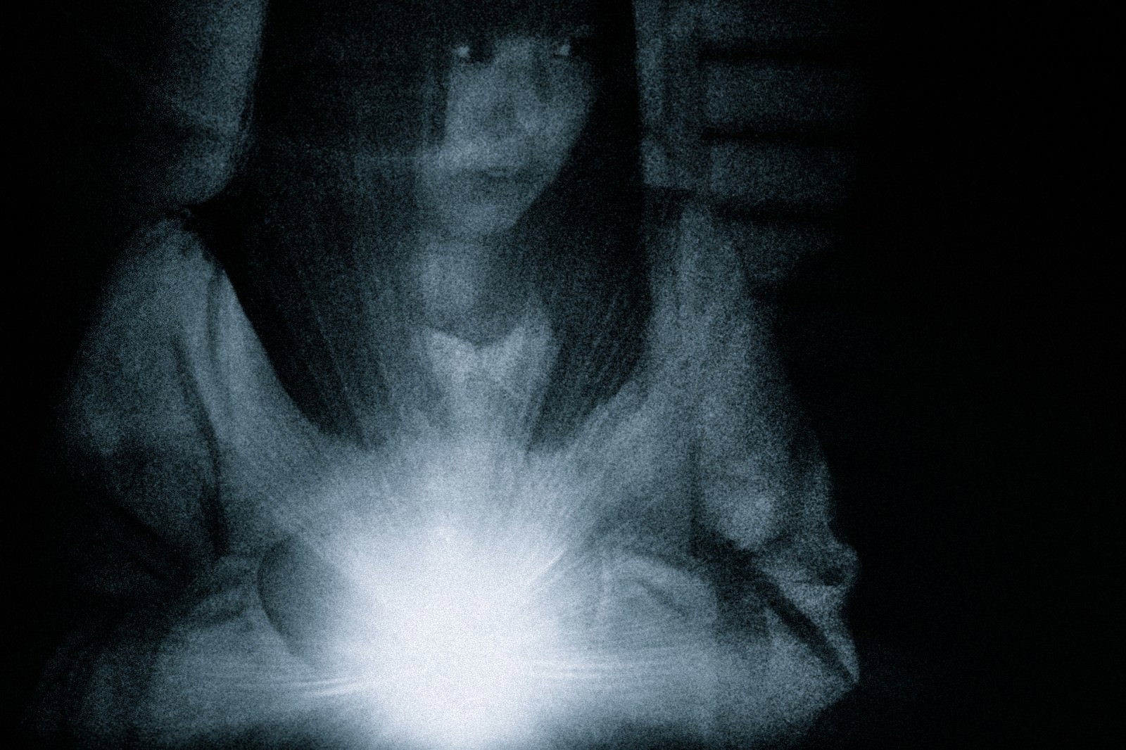 懐中電灯の光を頼りに暗闇を慎重に探索する女性［モデル：さとうゆい］