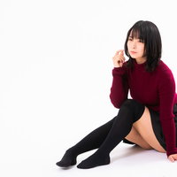 黒いハイソックスを履いて地べたに腰を下ろす女性の写真