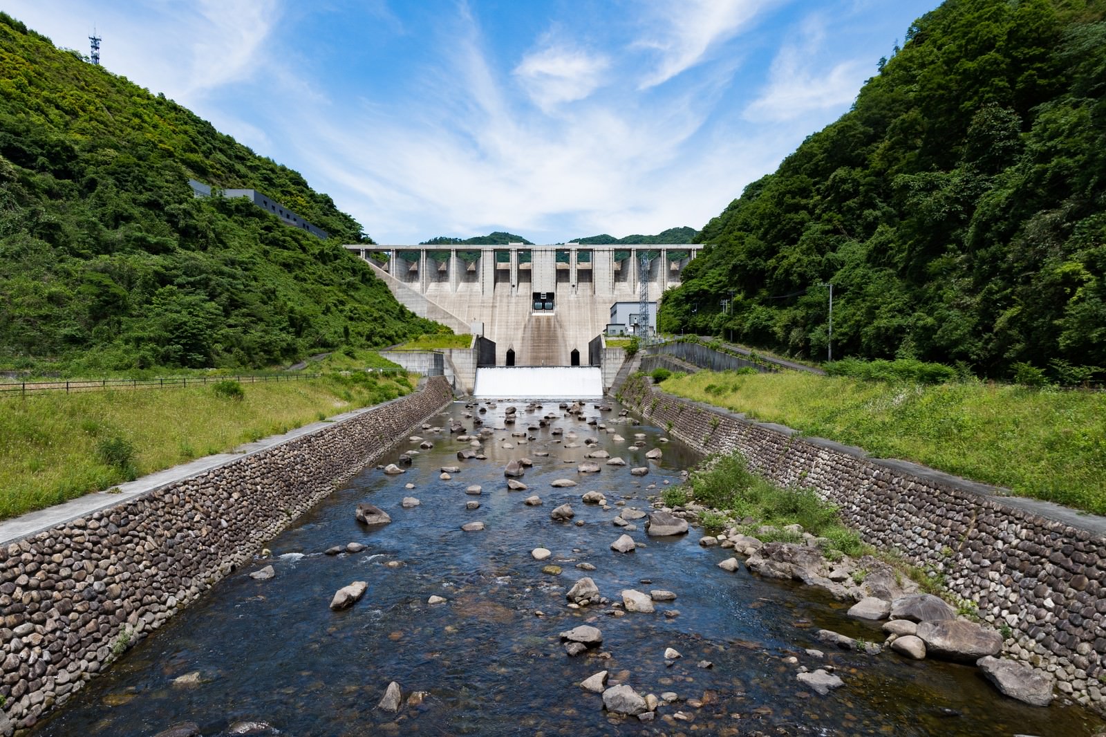 緑の山々に囲まれた苫田ダムと奥津湖、手前に石敷きの水路