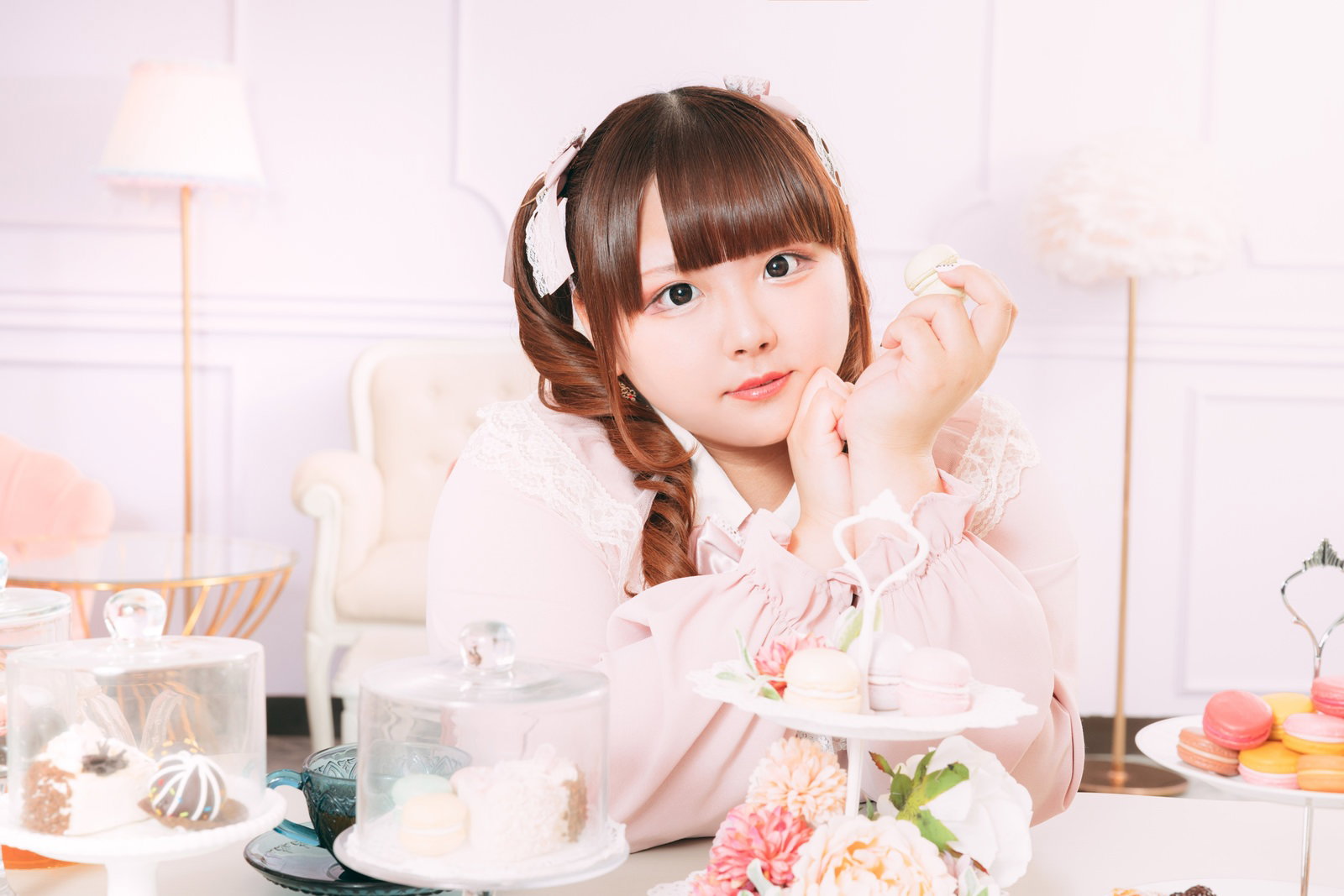 ピンクのワンピース姿でティータイム中、マカロンを手に取る女性［モデル：あづき］