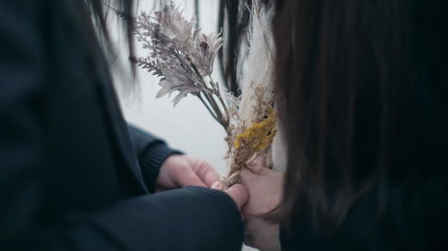 ドライフラワーの花束を握る女子高生の手元
