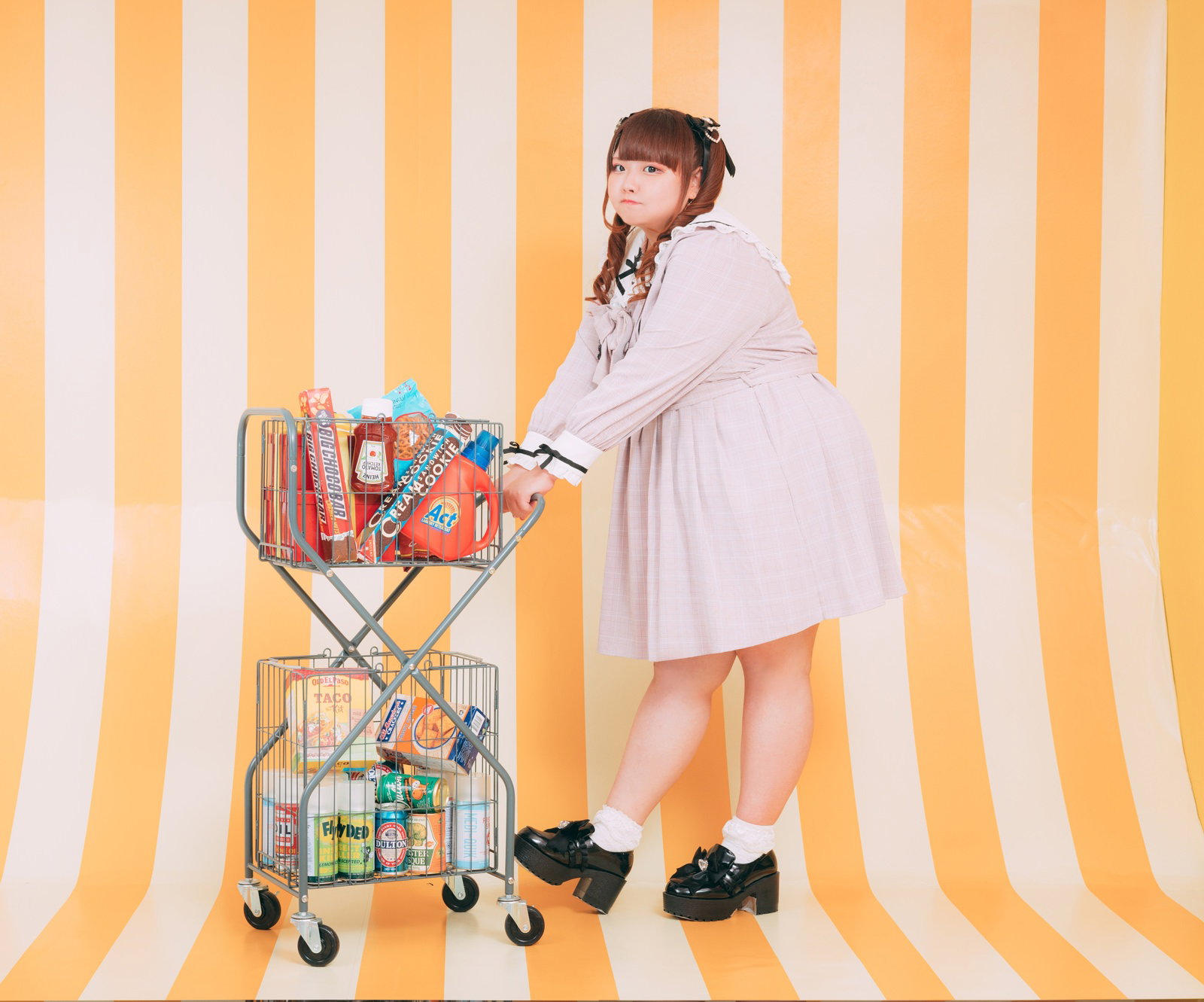ショッピングカートを押すツインテールの女性がカメラ目線で立っている［モデル：あづき］