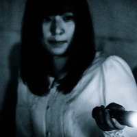 暗闇の中で懐中電灯に照らされた女性を発見した様子の写真