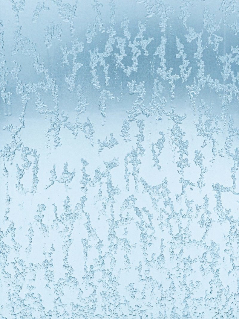 窓ガラスに付着した溶けかけた雪と結露の水滴が作る淡い青色のテクスチャー