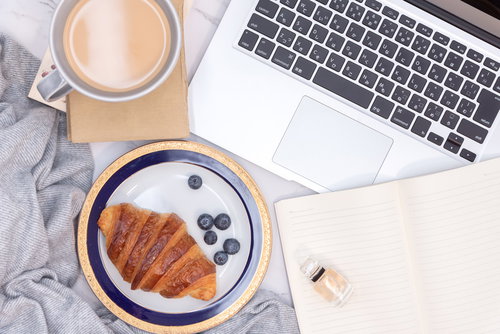 クロワッサンとティーカップが並ぶデスク周り