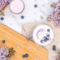木製テーブルに飾ったライラックとブルーベリーヨーグルトの写真