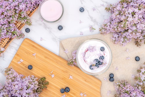 木製テーブルに飾ったライラックとブルーベリーヨーグルト