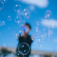 青空を背景にシャボン玉で遊ぶ子供たちの笑顔の写真