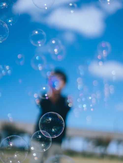 青空を背景にシャボン玉で遊ぶ子供たちの笑顔