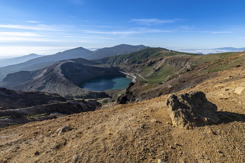 蔵王山の荒涼とした斜面に点在する噴石と御釜の火口湖