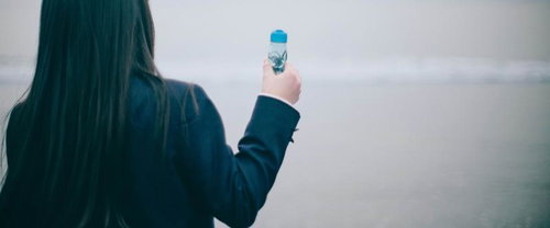 映画のような一瞬、ラムネの瓶を掲げた女子高生の後ろ姿